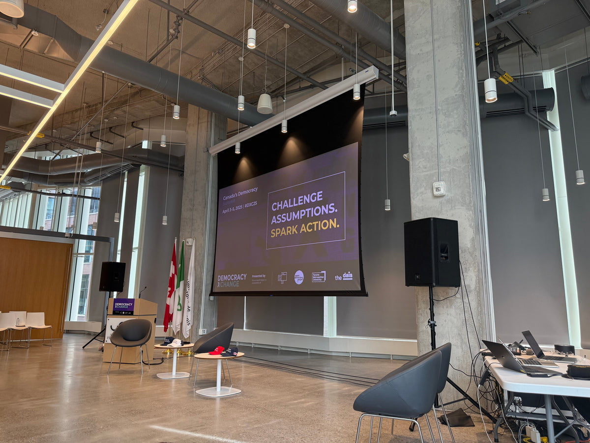 DemocracyXChange presentation space with a stage, screen and Canadian flag