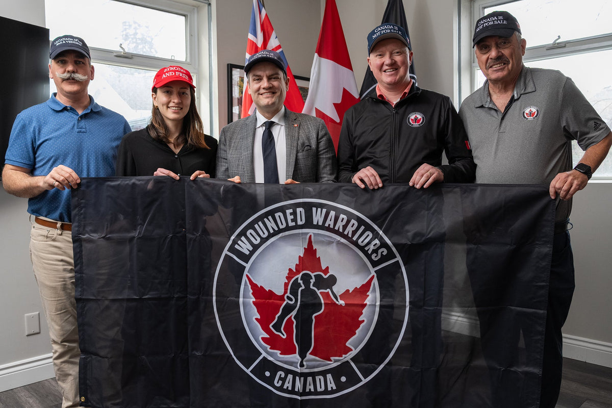 Group holding a Wounded Warriors Canada banner with Canadian flags behind them
